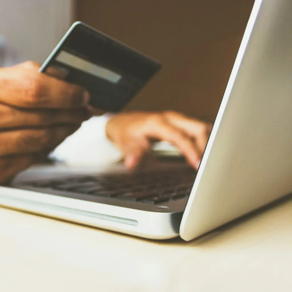 person using laptop computer holding card